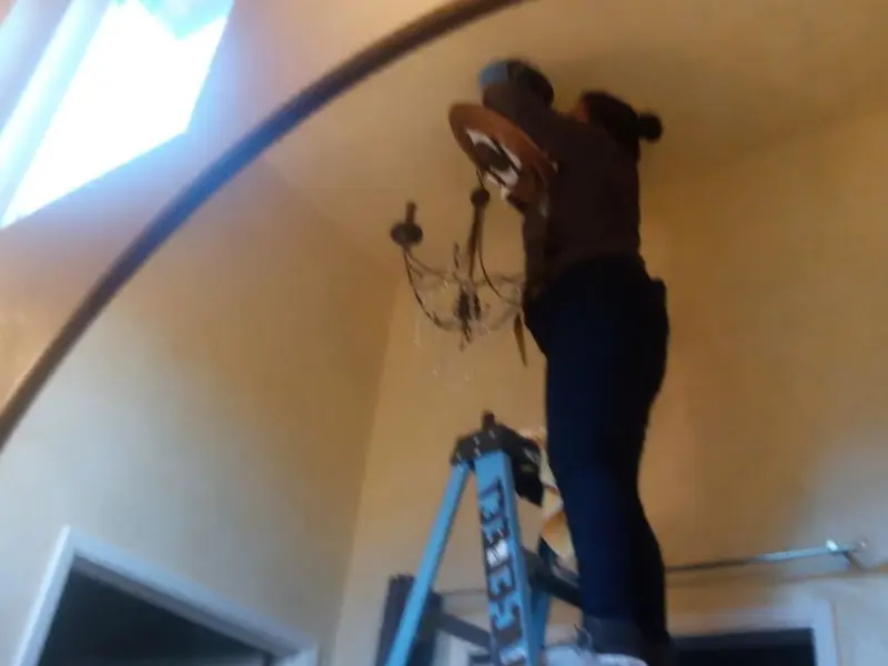 Electrician installing a chandelier in a Chatham residence